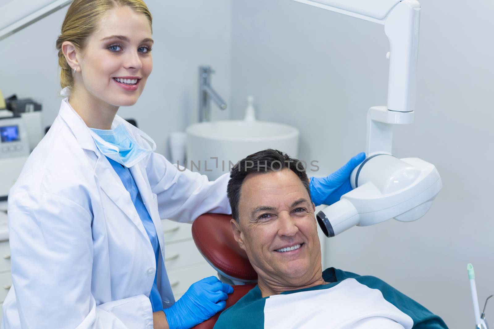 Portrait of dentist examining a male patient with dental tool in clinic