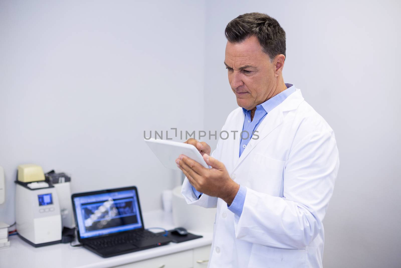 Attentive dentist using digital tablet in clinic
