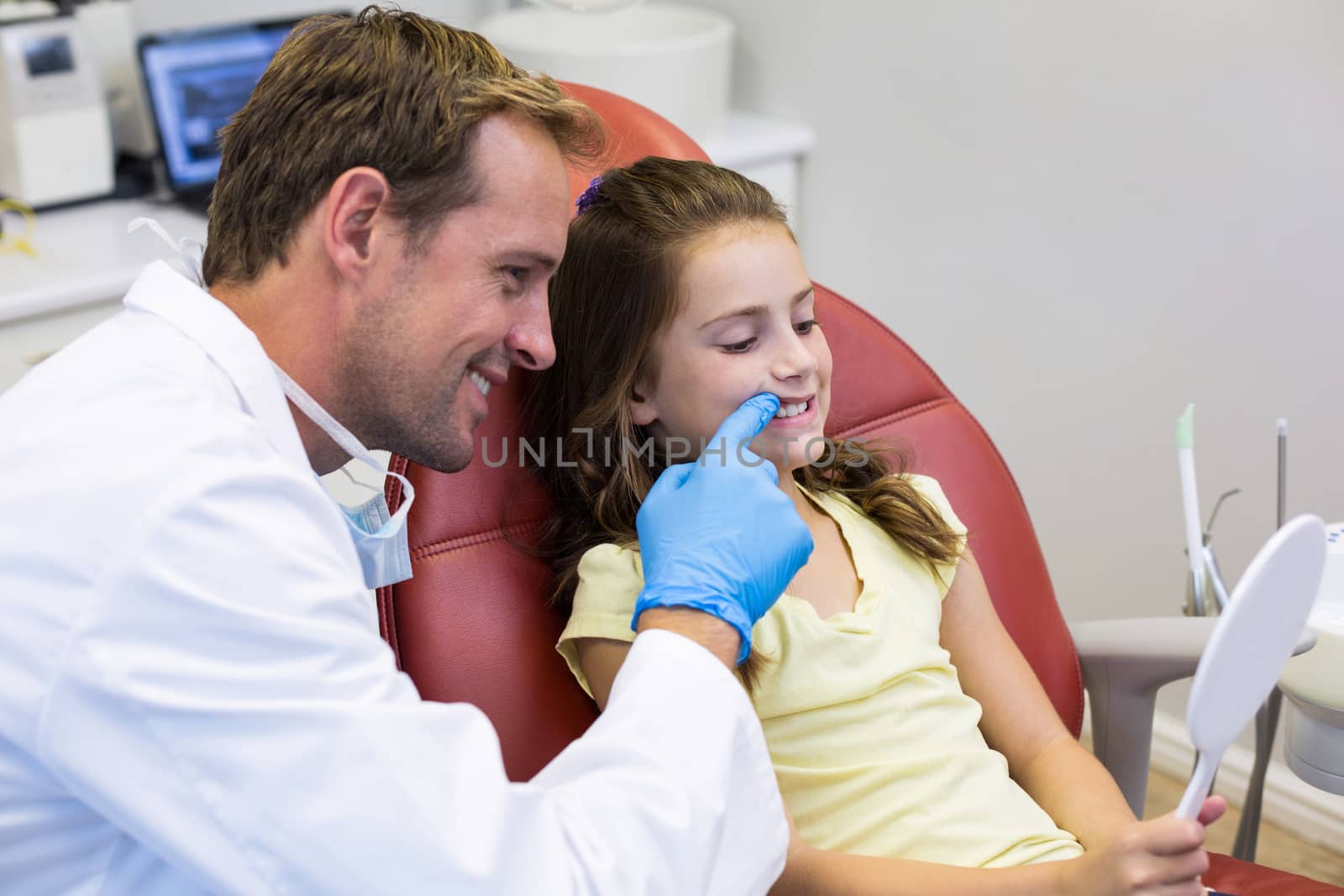 Smiling young patient looking in the mirror with a dentist in dental clinic