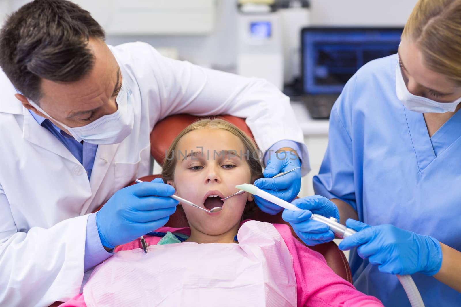 Dentist and nurse examining a young patient with tools by Wavebreakmedia