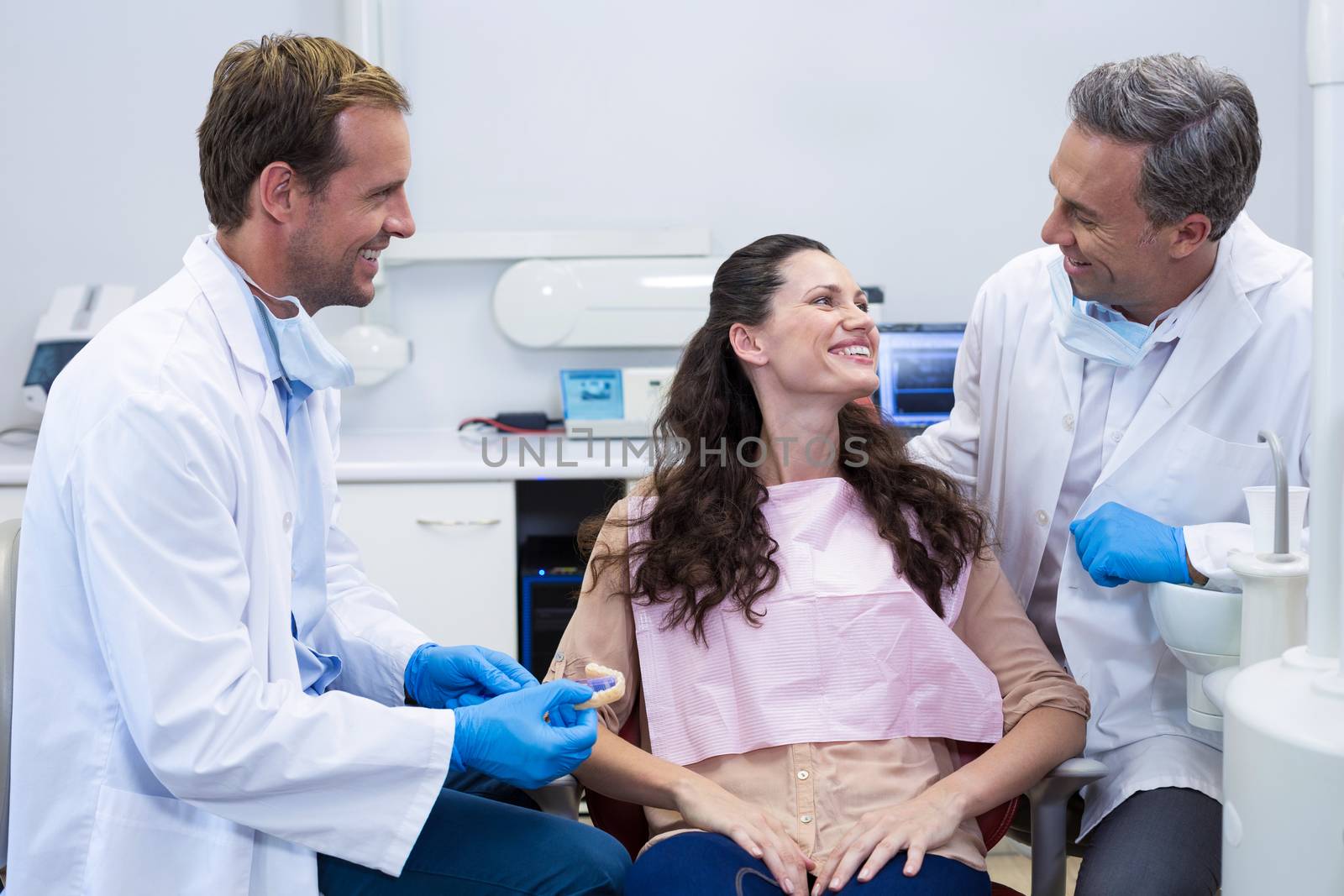 Dentist showing model teeth to patient in dental clinic