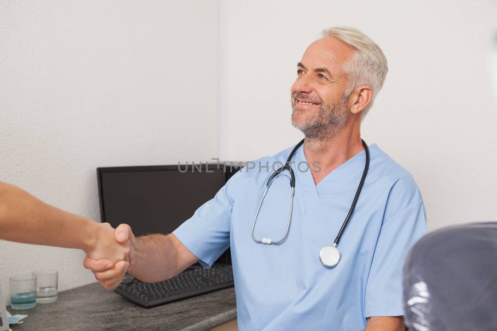 Dentist shaking hands with his patient at the dental clinic