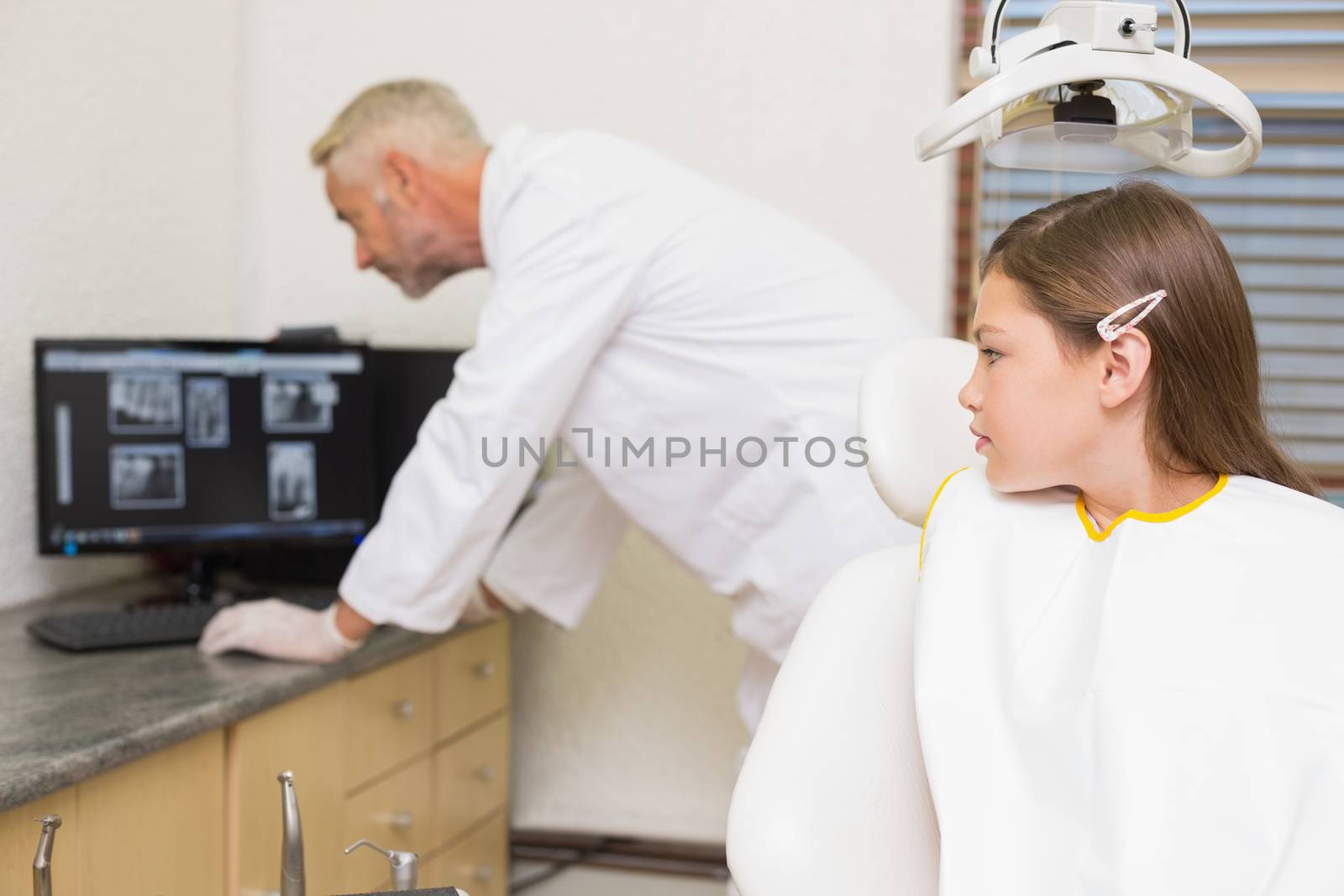 Little girl watching dentist looking at xrays at the dental clinic