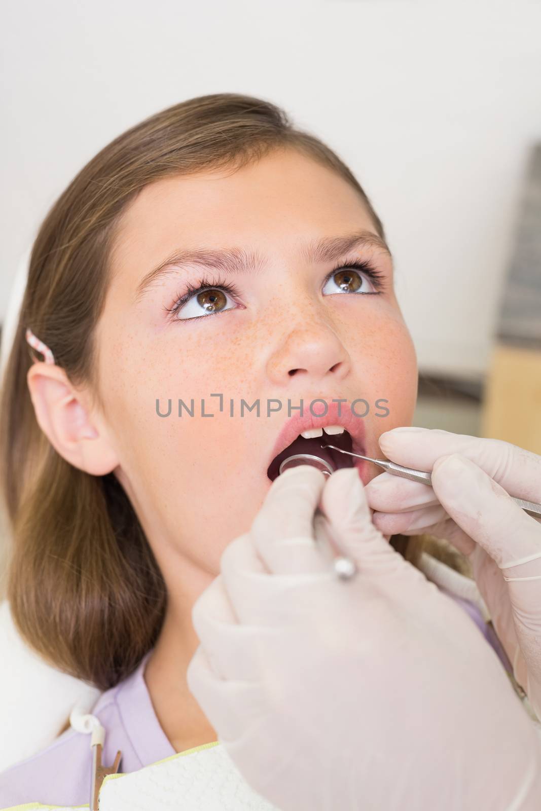 Pediatric dentist examining little girls teeth in the dentists chair at the dental clinic