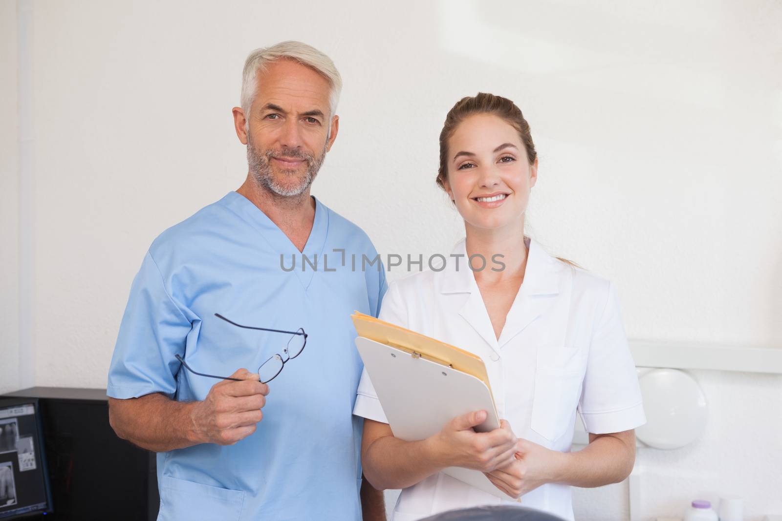 Dentist and assistant smiling at camera at the dental clinic