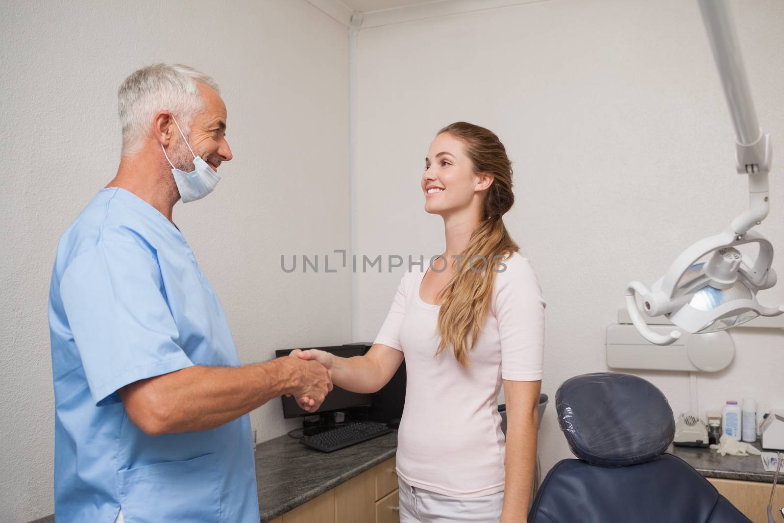 Dentist shaking hands with his patient at the dental clinic