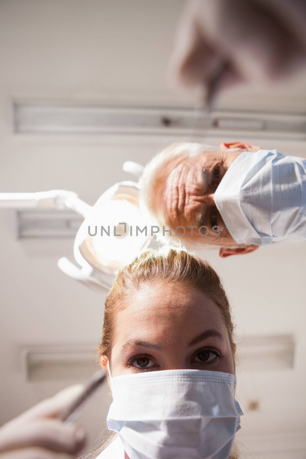 Dentist and assistant leaning over patient with tools at the dental clinic