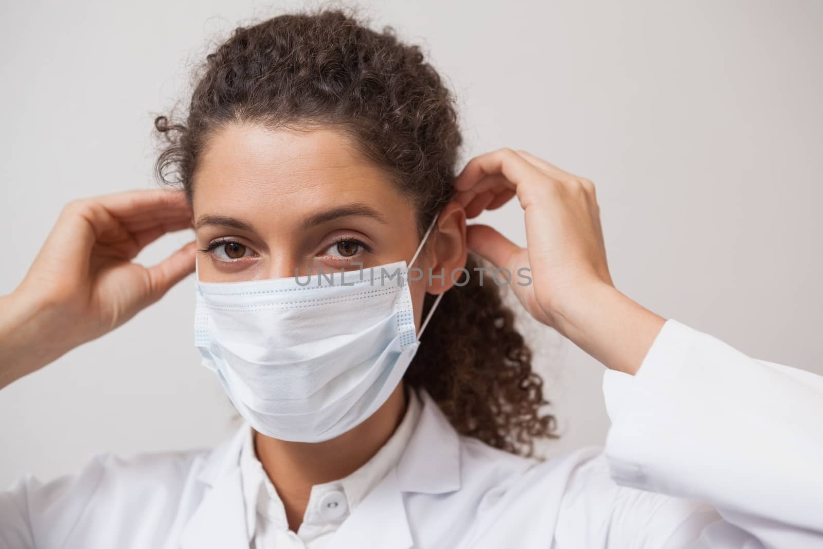Dentist putting on surgical mask looking at camera at the dental clinic