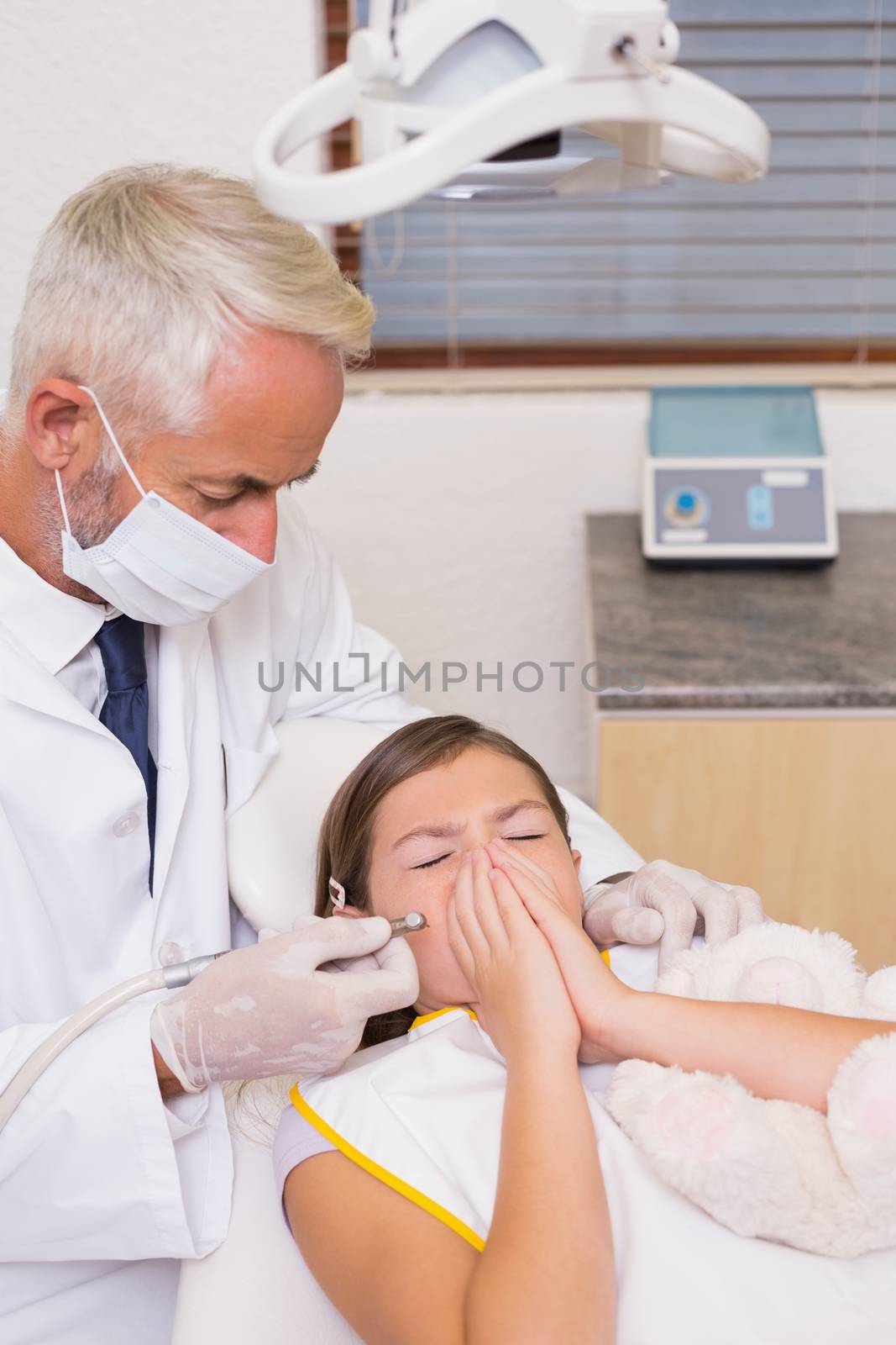Pediatric dentist trying to see sneezing patients teeth at the dental clinic
