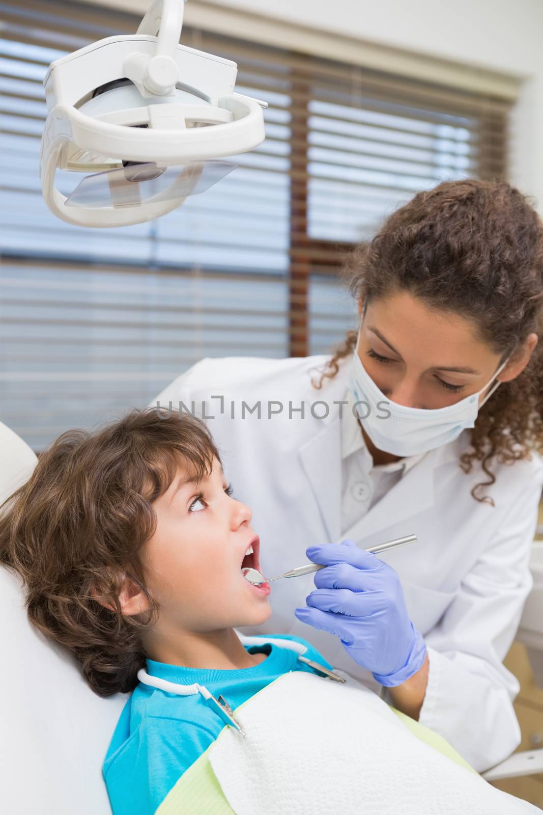 Pediatric dentist examining a little boys teeth in the dentists chair at the dental clinic