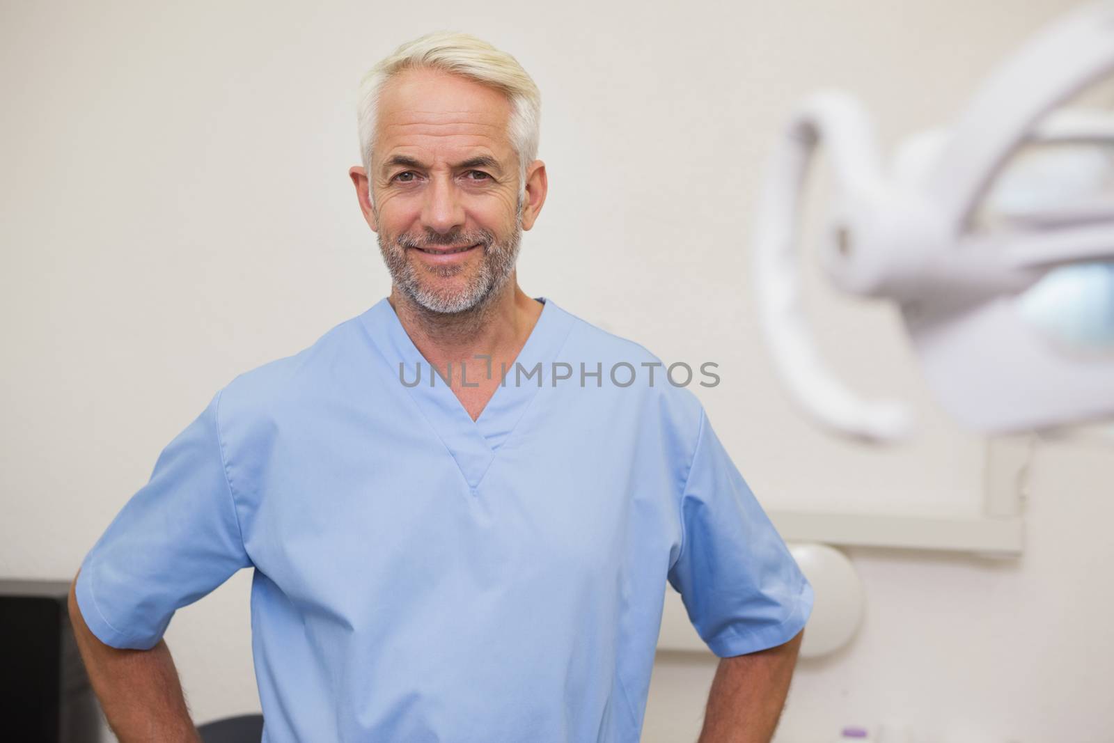 Dentist smiling at camera in blue scrubs at the dental clinic