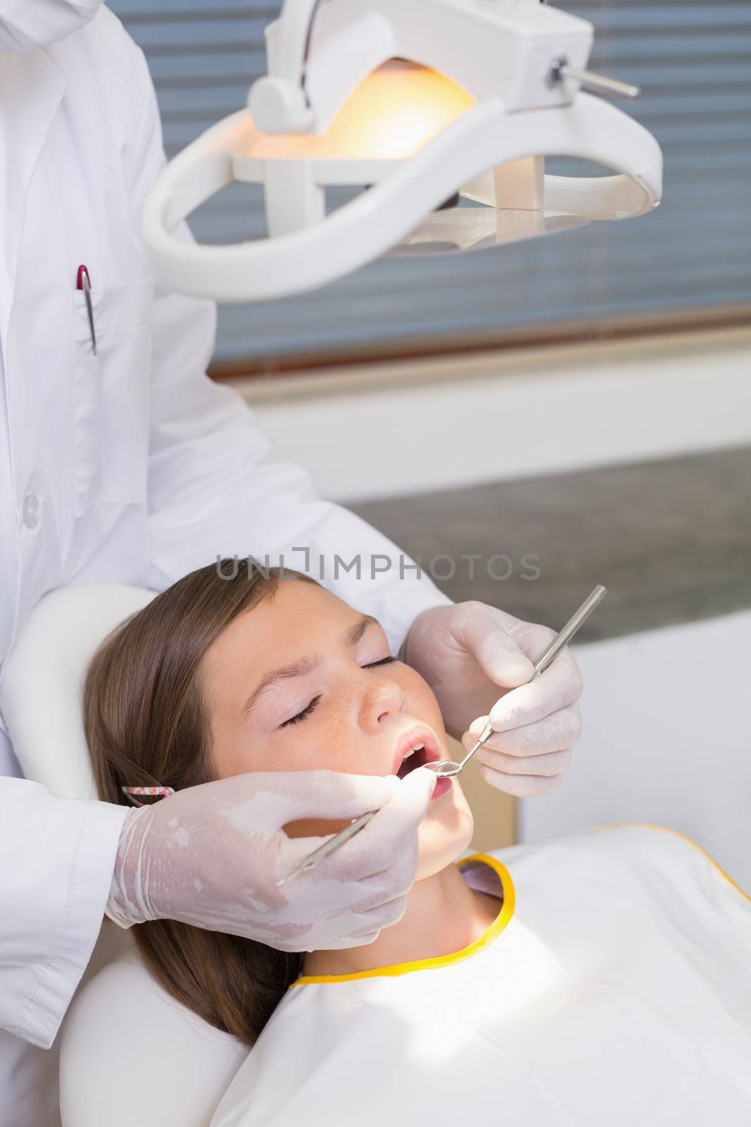 Pediatric dentist examining a patients teeth in the dentists chair by Wavebreakmedia