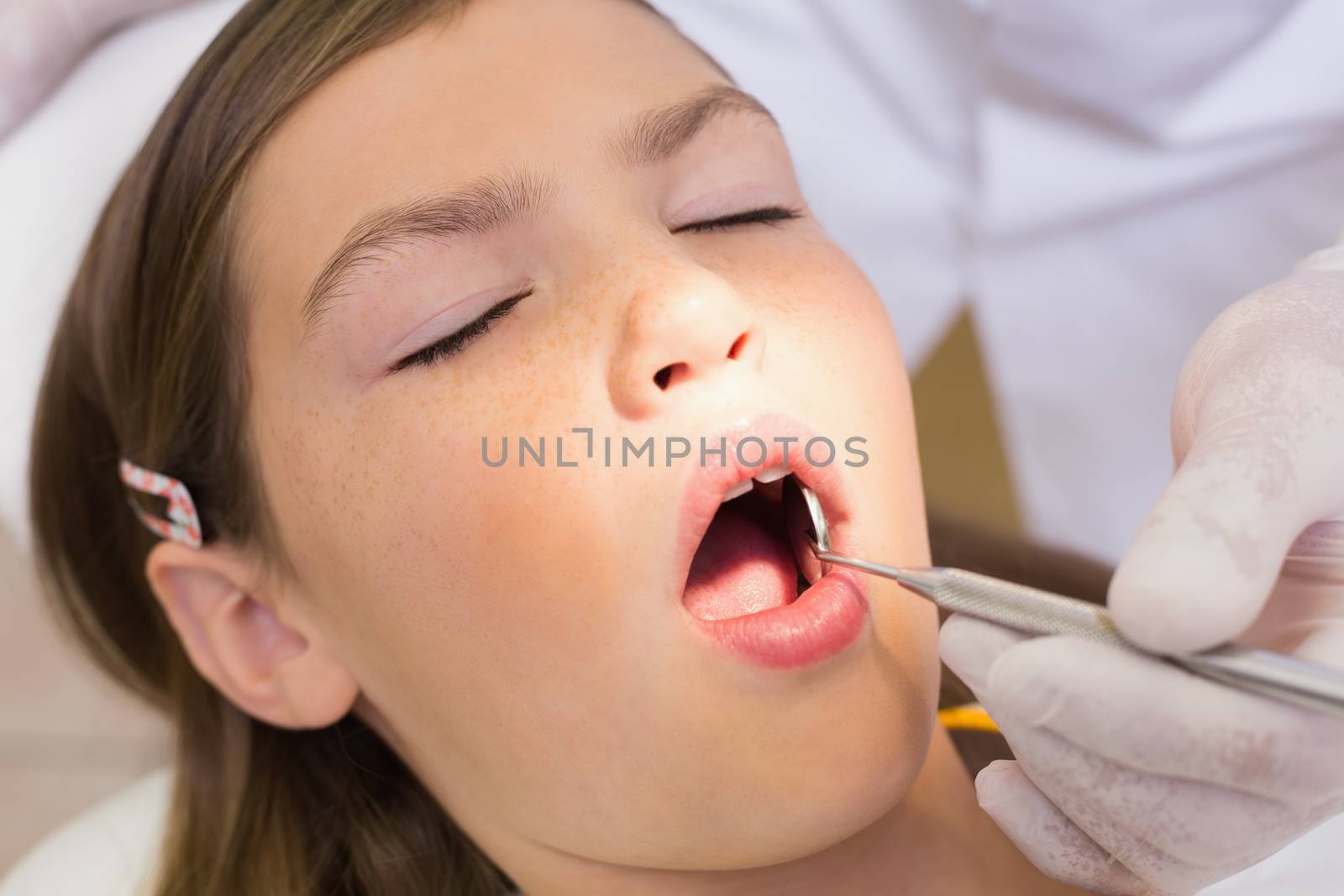 Pediatric dentist examining a patients teeth in the dentists chair by Wavebreakmedia