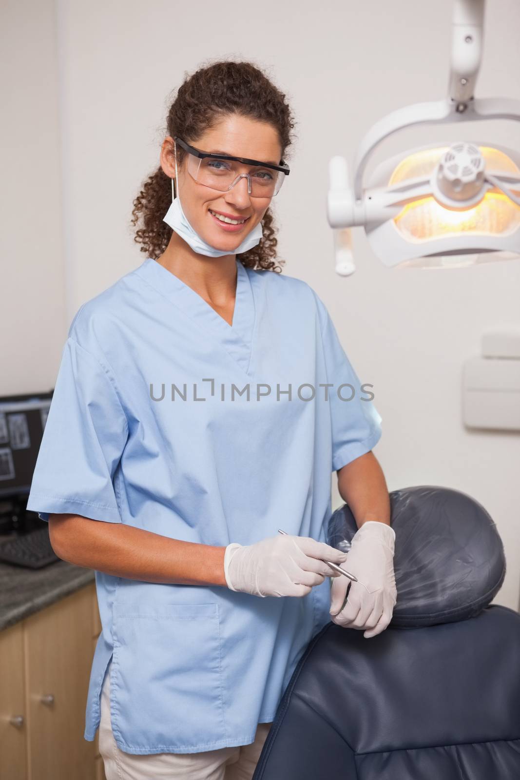 Dentist in blue scrubs smiling at camera  by Wavebreakmedia
