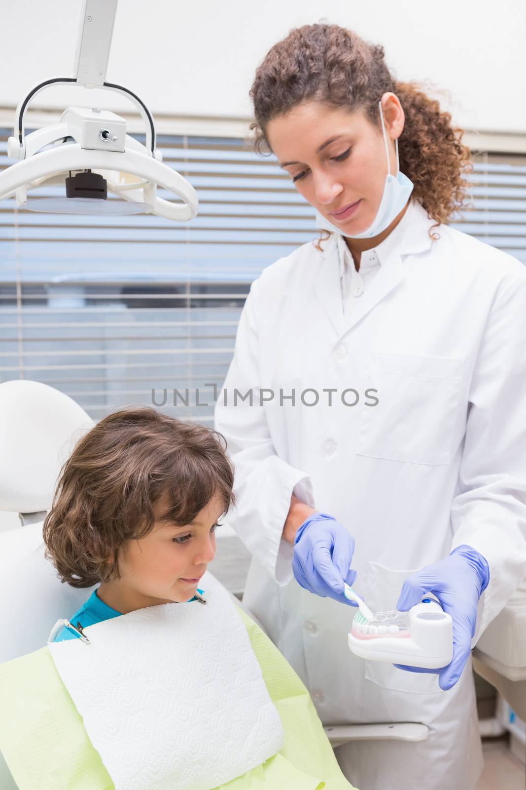 Pediatric dentist showing little boy teeth model by Wavebreakmedia