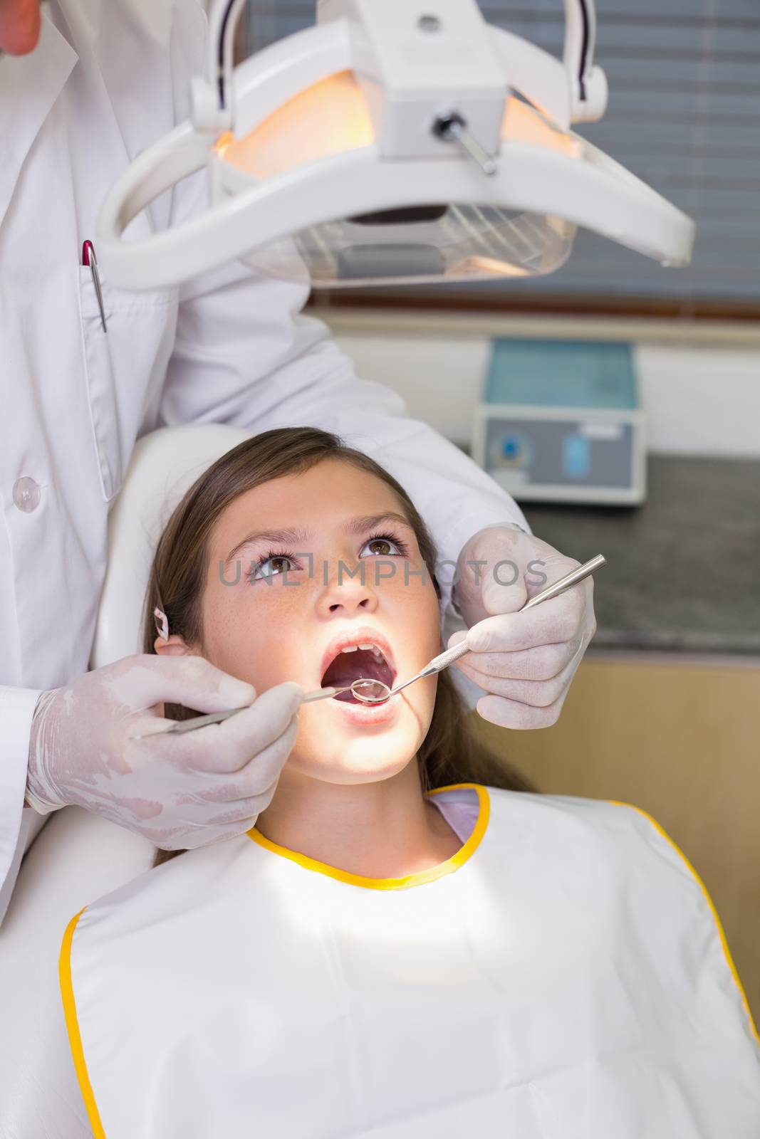 Pediatric dentist examining a patients teeth in the dentists chair at the dental clinic