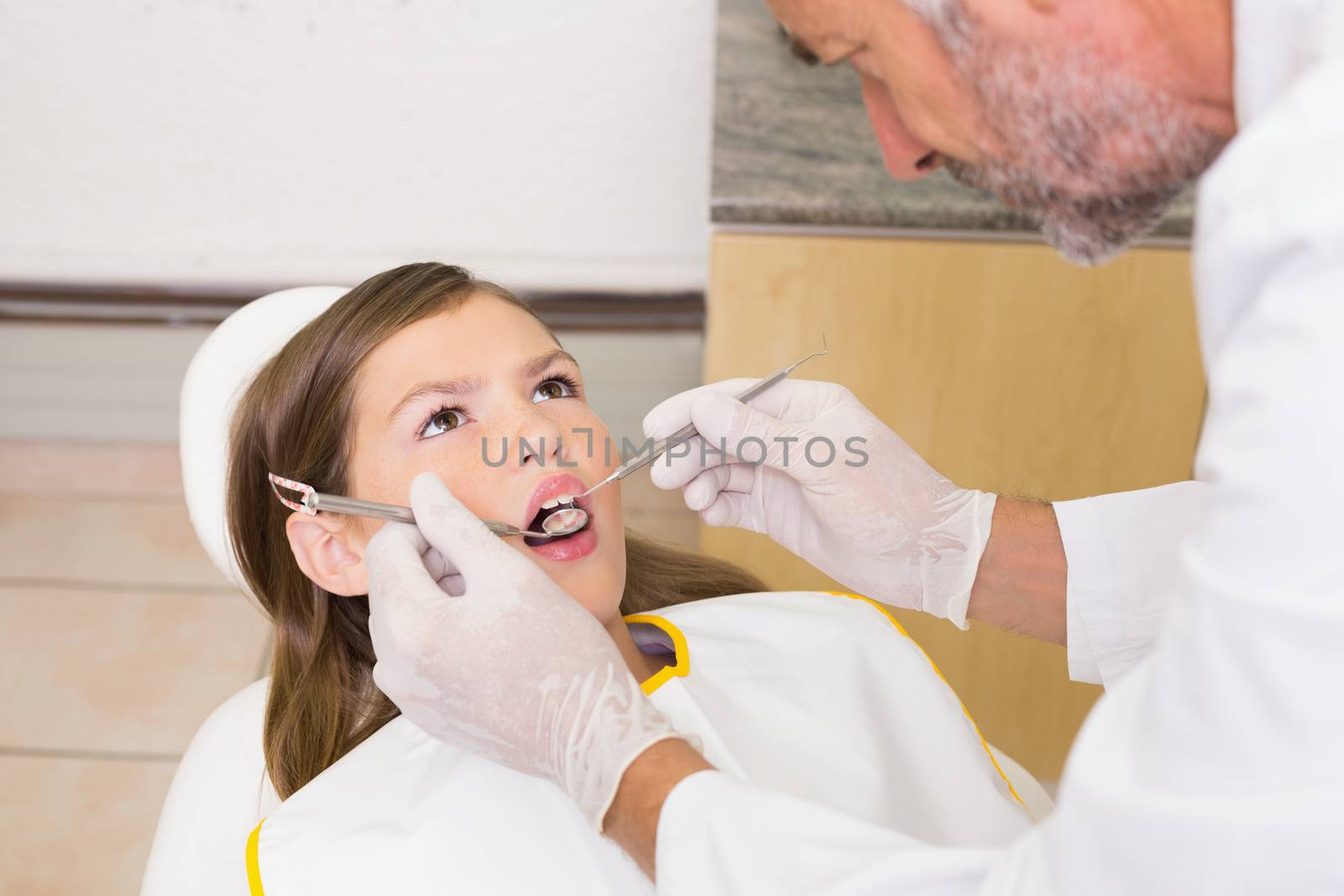 Pediatric dentist examining a patients teeth in the dentists chair by Wavebreakmedia