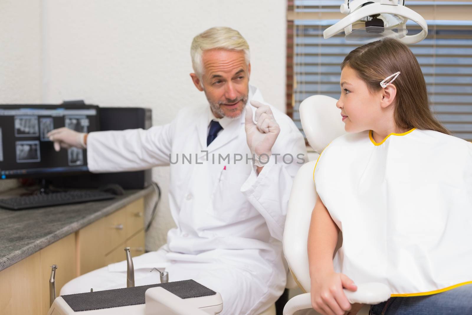 Dentist explaining xrays to little girl at the dental clinic