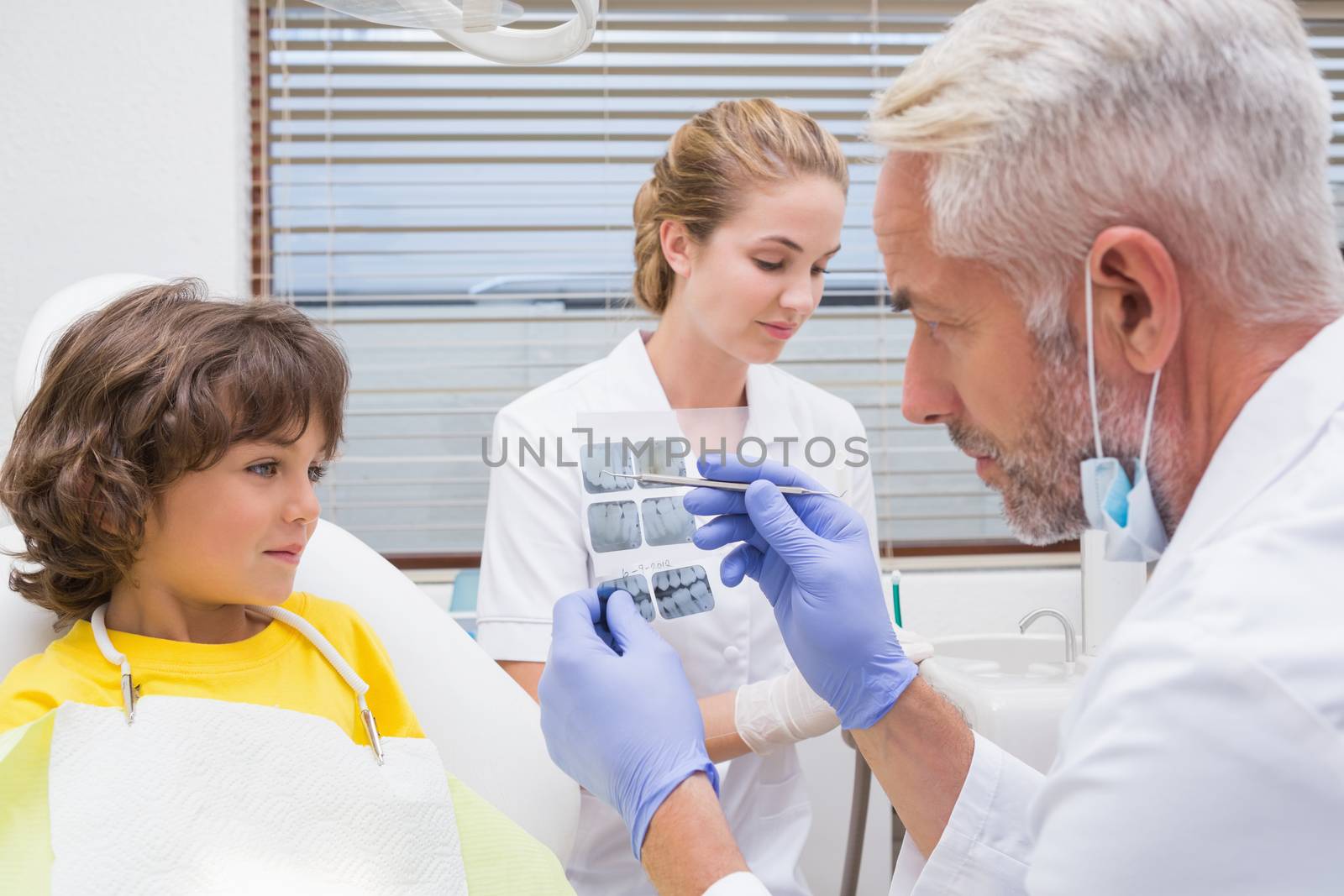 Pediatric dentist showing little boy his mouth xray at the dental clinic