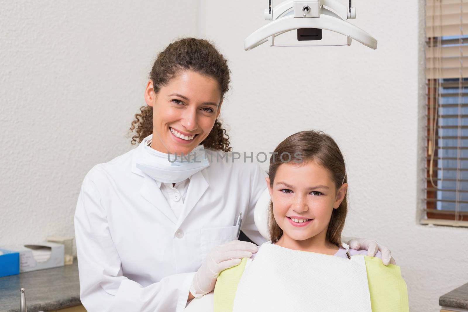 Little girl smiling at camera with her pediatric dentist by Wavebreakmedia