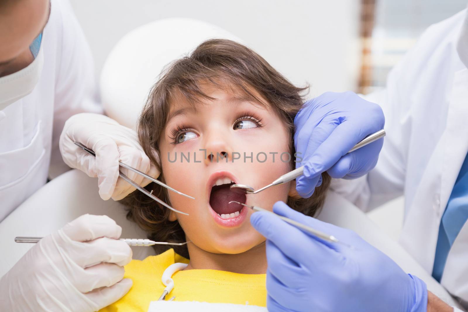 Pediatric dentist examining a little boys teeth with his assistant  by Wavebreakmedia