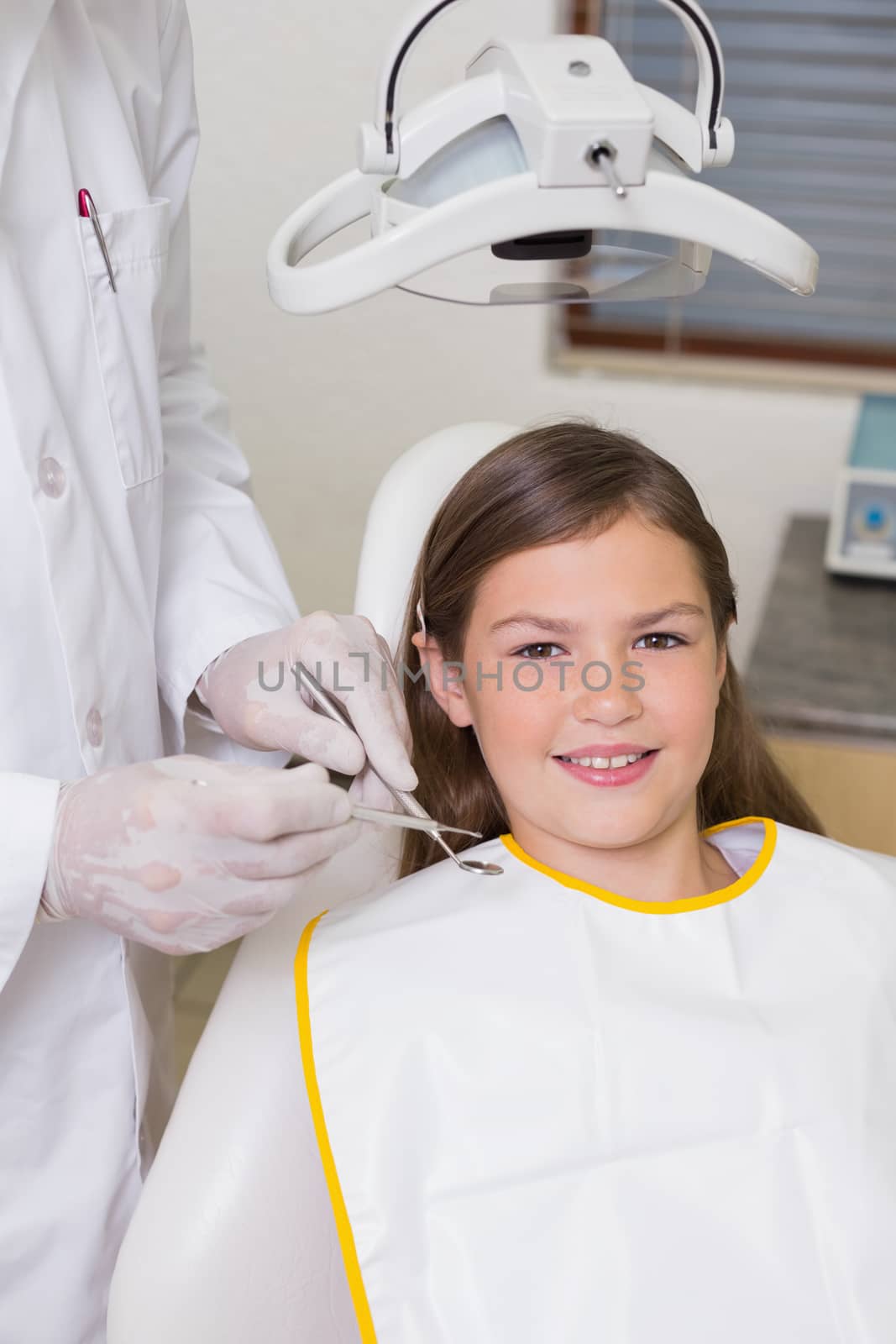 Little girl sitting in dentists chair smiling at camera by Wavebreakmedia