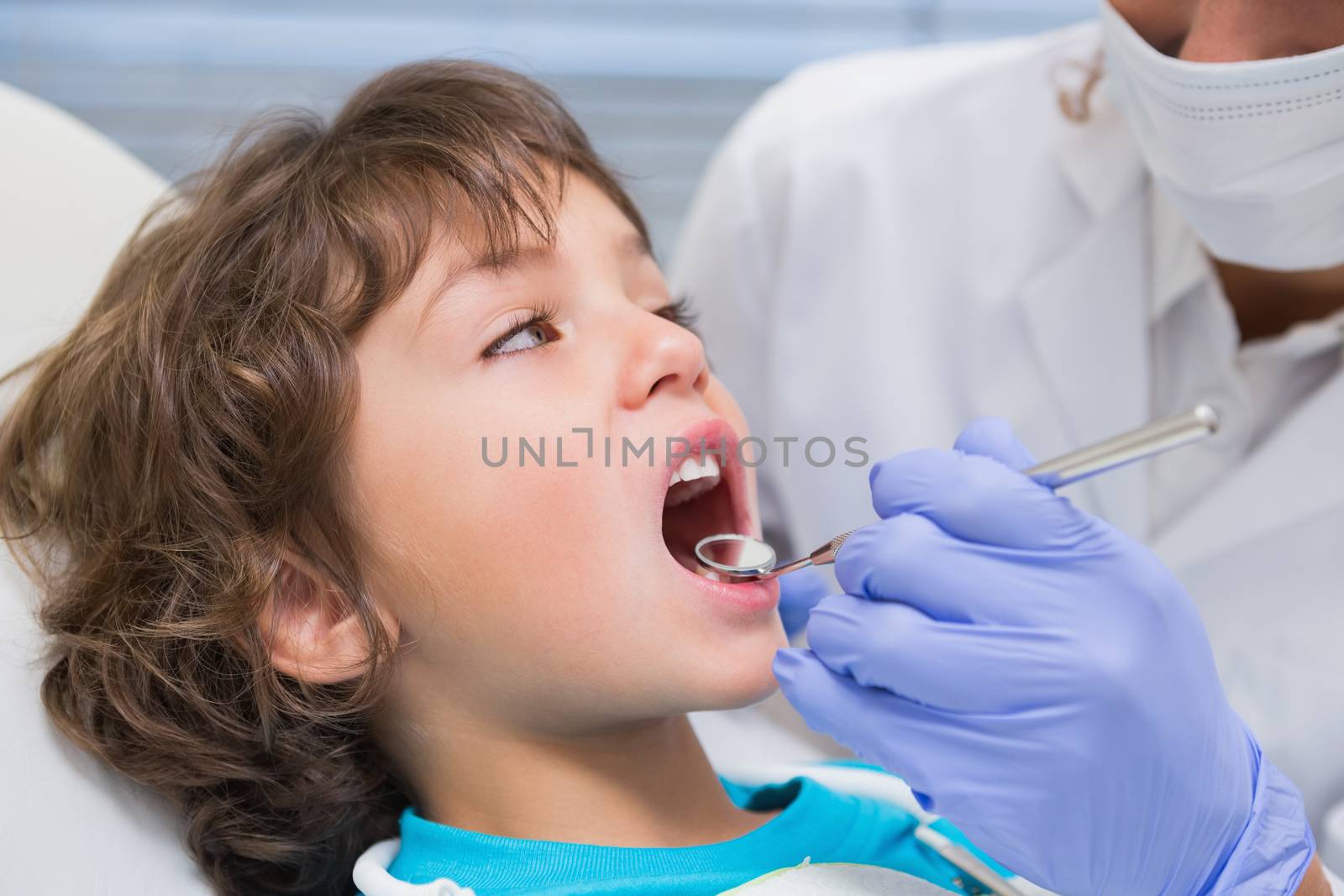 Pediatric dentist examining a little boys teeth in the dentists chair by Wavebreakmedia