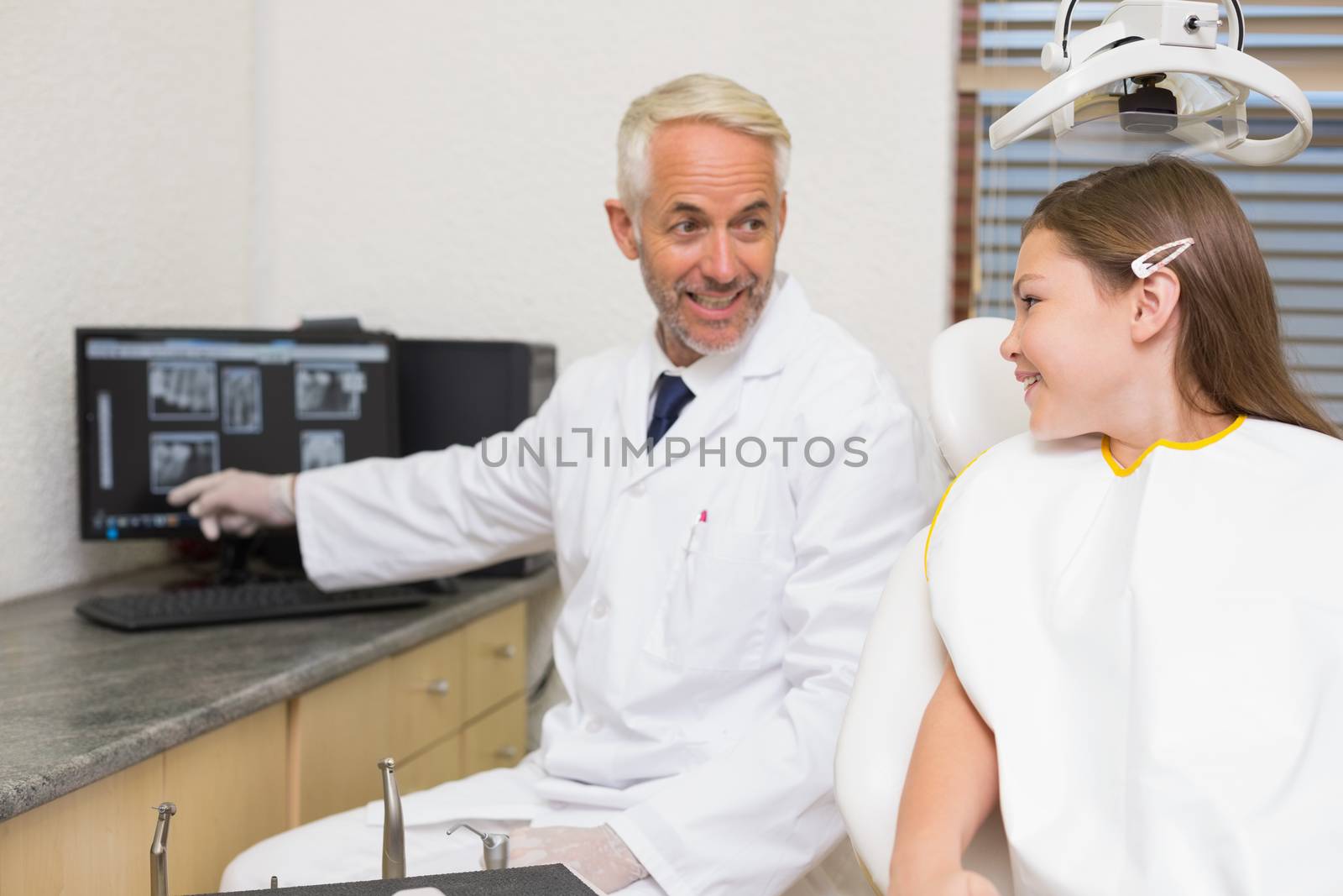 Dentist explaining xrays to little girl at the dental clinic