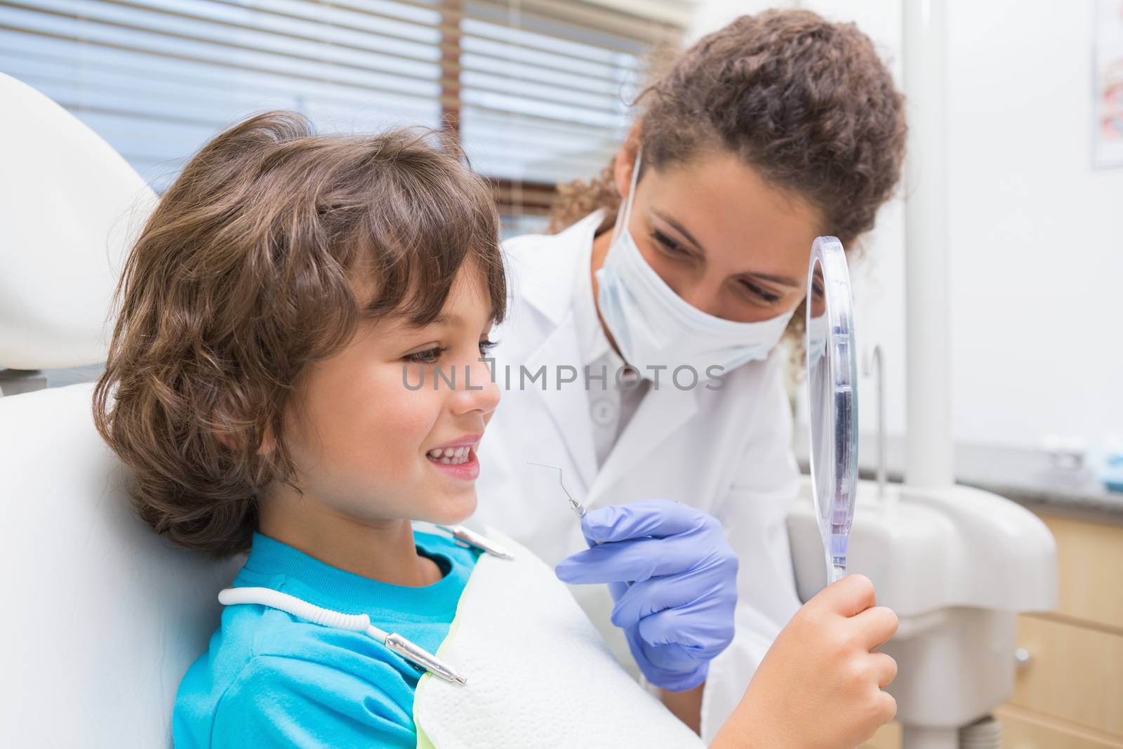 Pediatric dentist showing little boy his teeth in the mirror by Wavebreakmedia