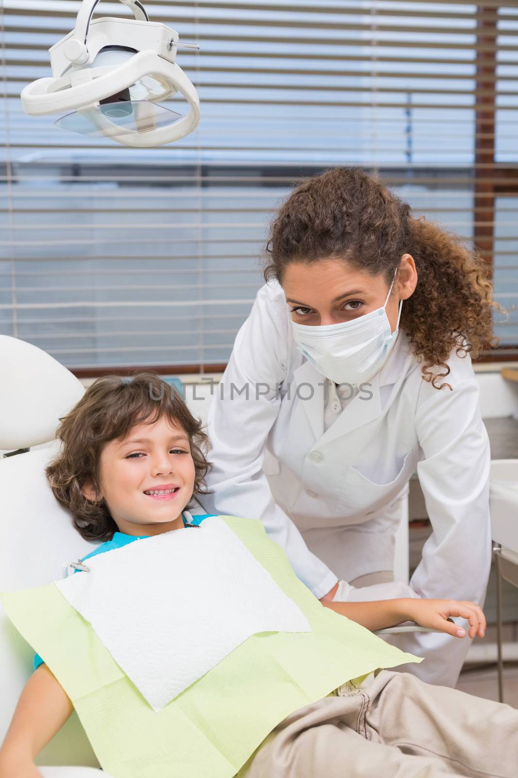 Pediatric dentist smiling with little boy in chair at the dental clinic