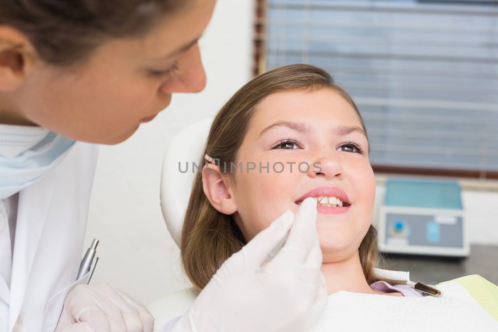 Pediatric dentist examining little girls teeth in the dentists chair by Wavebreakmedia