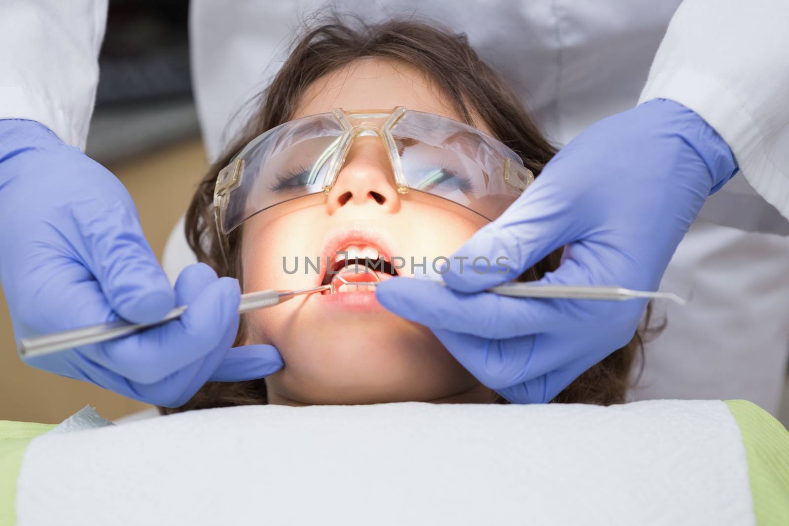 Pediatric dentist examining a little boys teeth in the dentists chair at the dental clinic