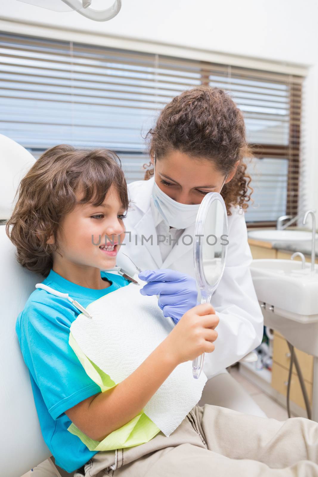 Pediatric dentist showing little boy his teeth in the mirror by Wavebreakmedia