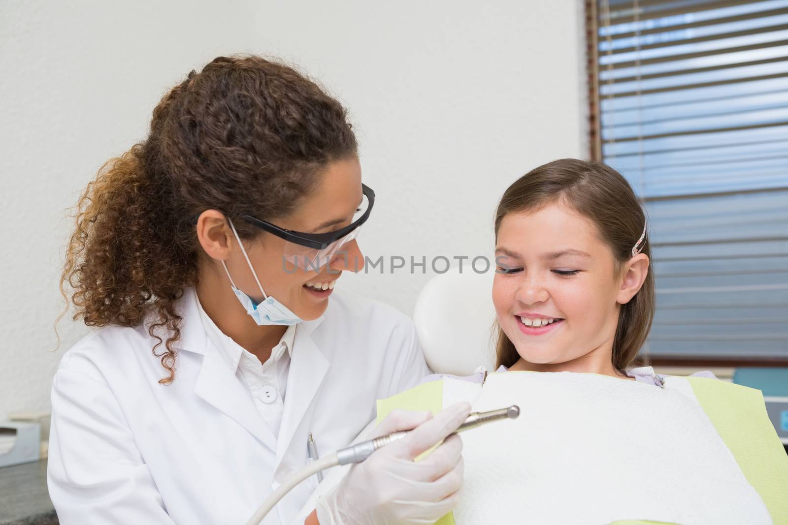 Pediatric dentist smiling with little girl in the chair by Wavebreakmedia