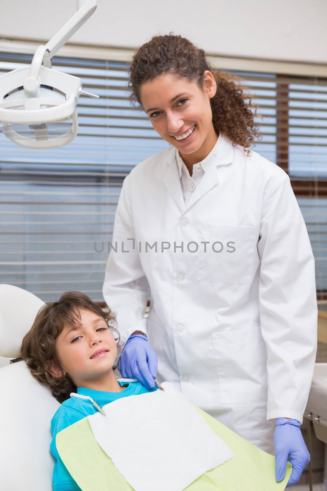 Pediatric dentist smiling with little boy in the chair at the dental clinic