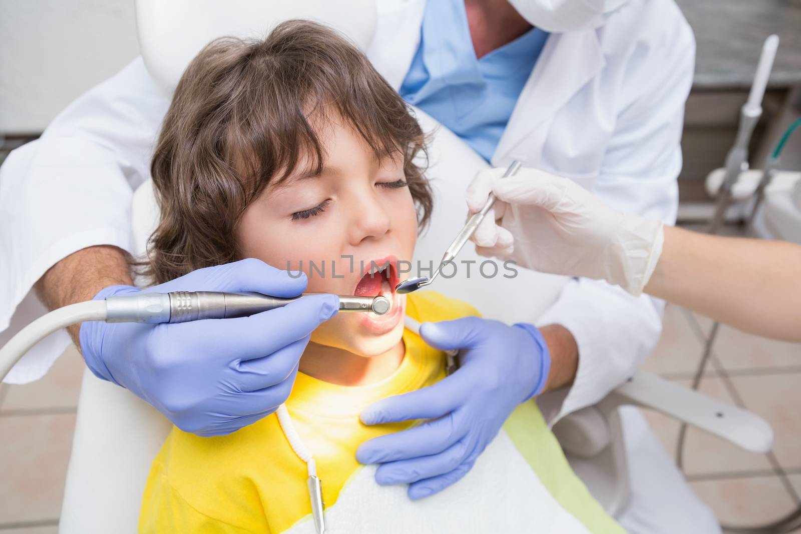 Pediatric dentist examining a little boys teeth in the dentists chair by Wavebreakmedia