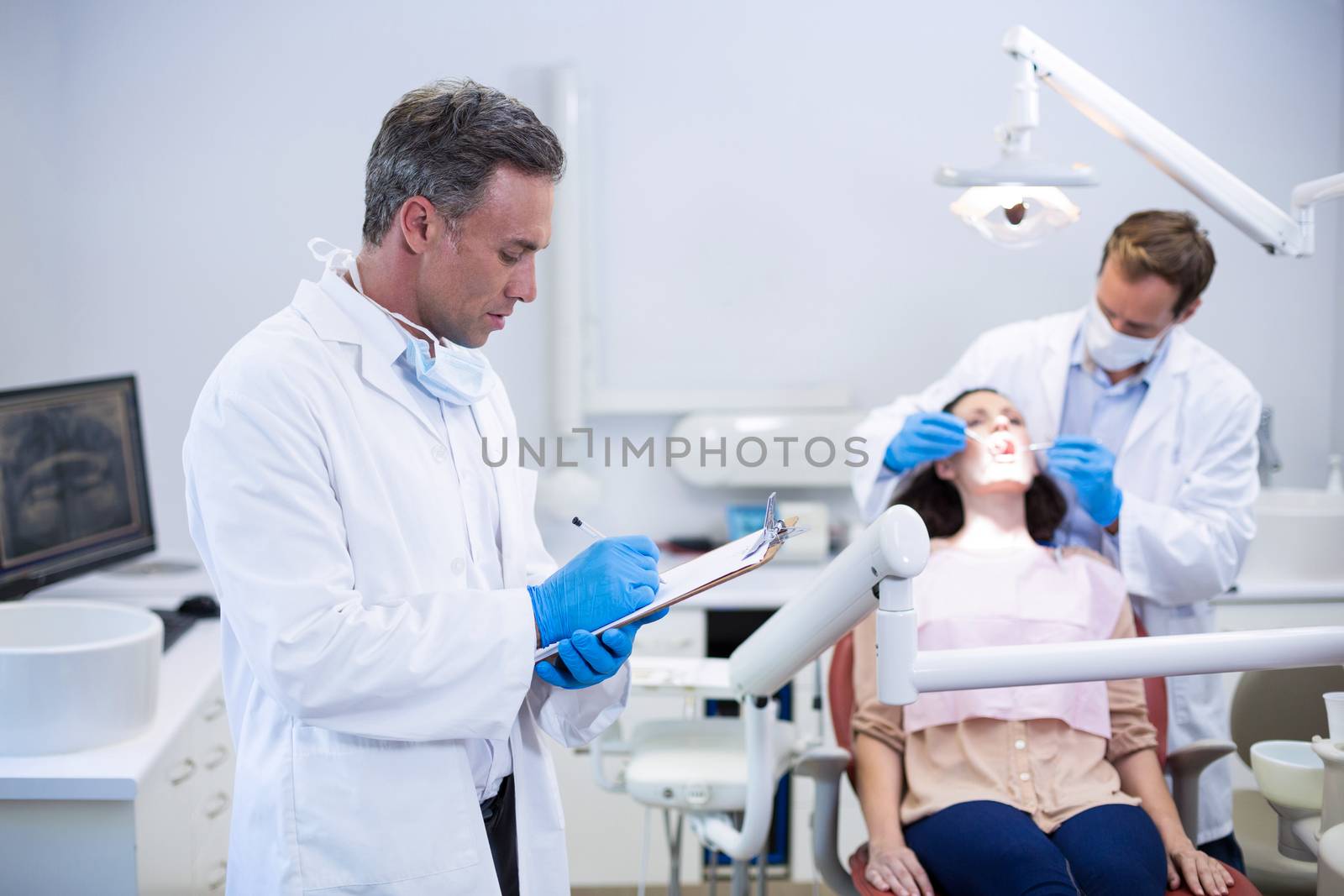 Dentist writing on clipboard in dental clinic