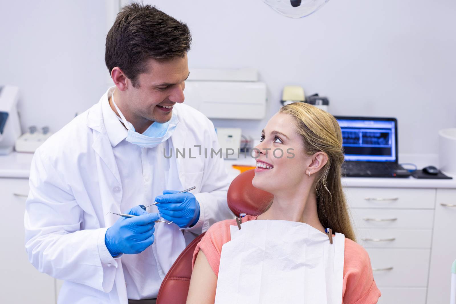 Dentist interacting with female patient while examining by Wavebreakmedia