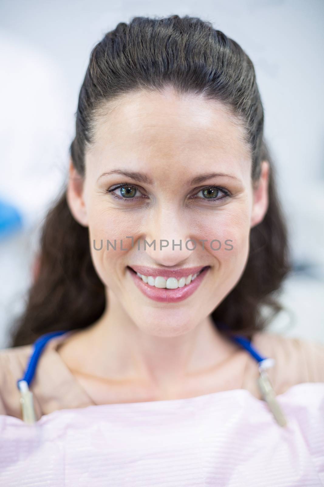 Smiling female patient sitting on dentist chair by Wavebreakmedia