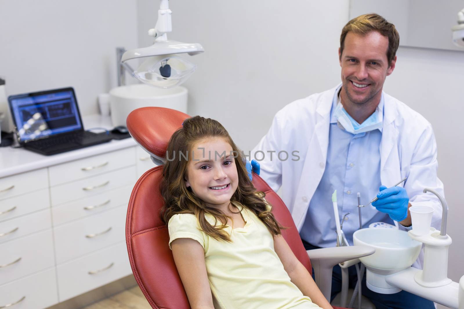 Portrait of smiling dentist and young patient in dental clinic