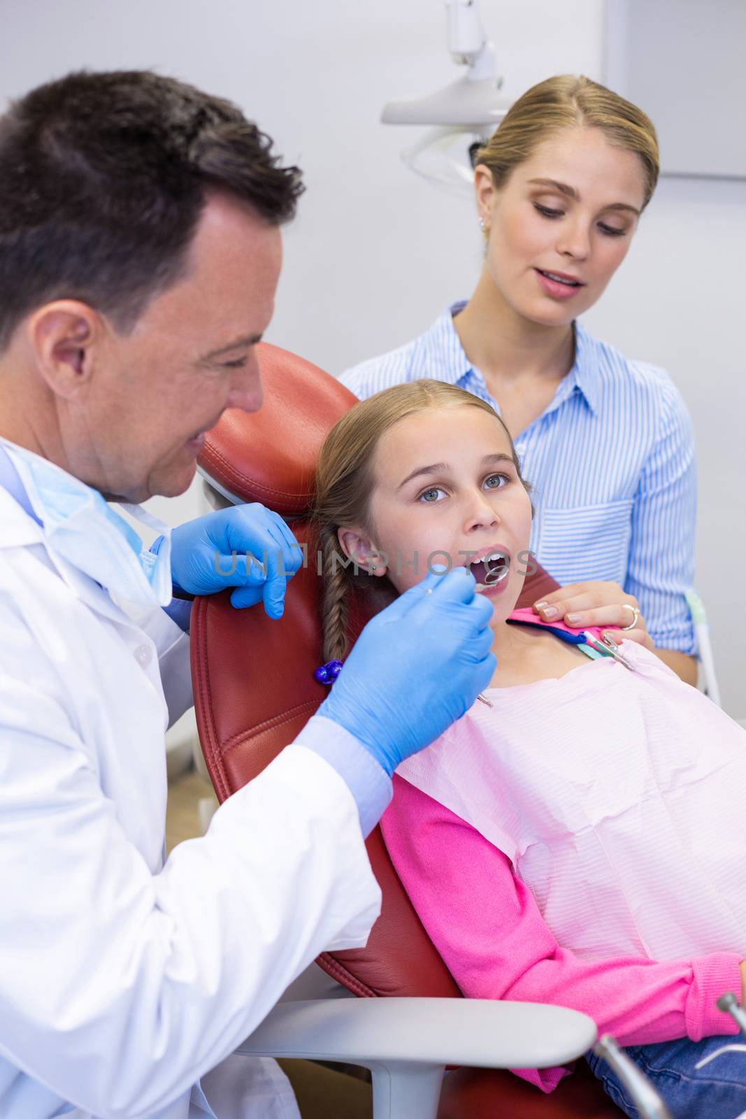 Dentist examining with young patient at dental clinic