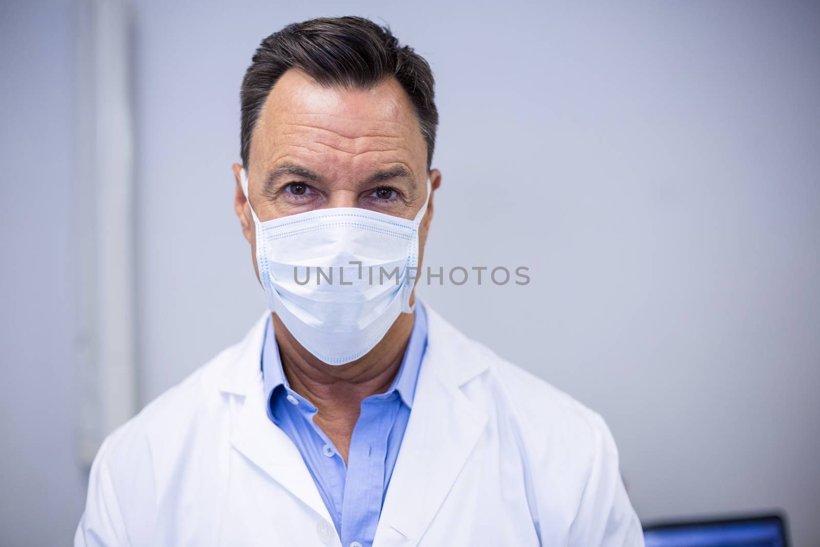 Dentist wearing surgical mask in dental clinic by Wavebreakmedia