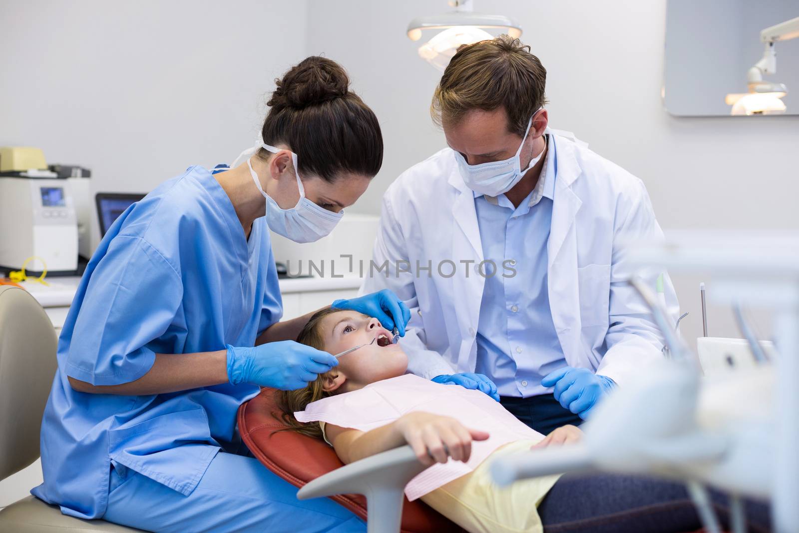 Dentist examining a young patient with tools in dental clinic