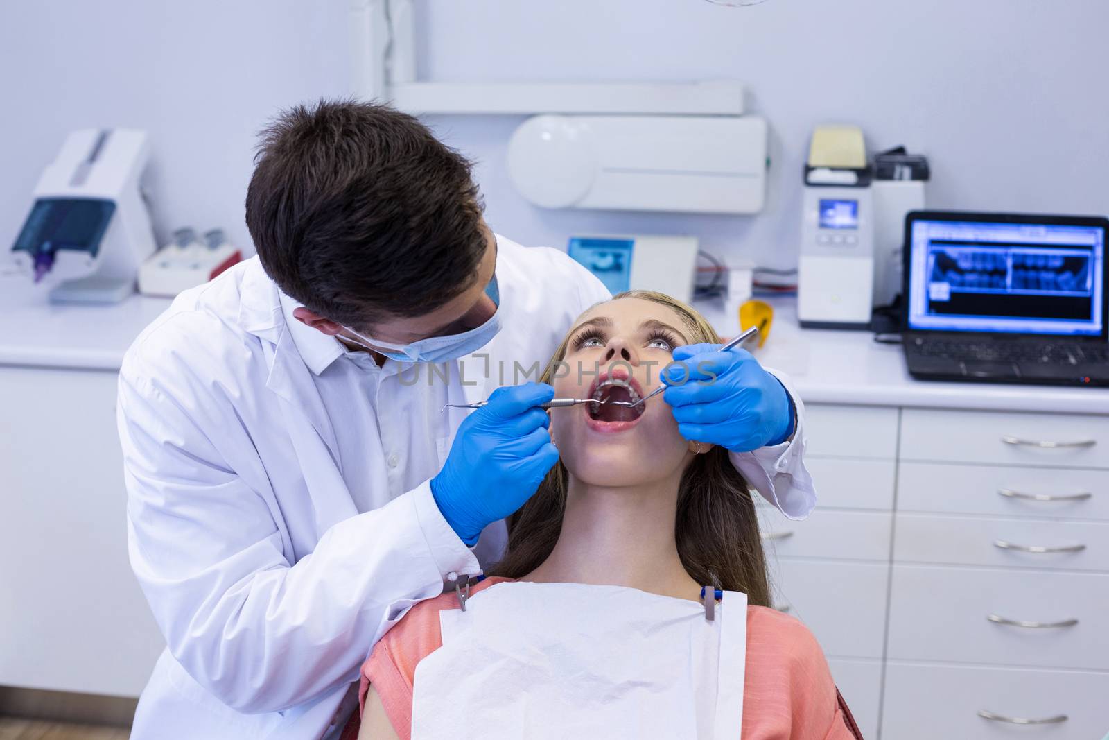 Dentist examining a female patient with tools by Wavebreakmedia