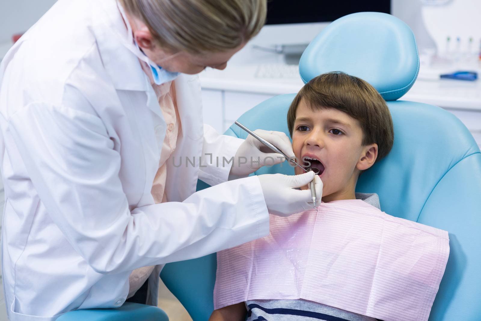 Boy receiving dental treatment by dentist by Wavebreakmedia