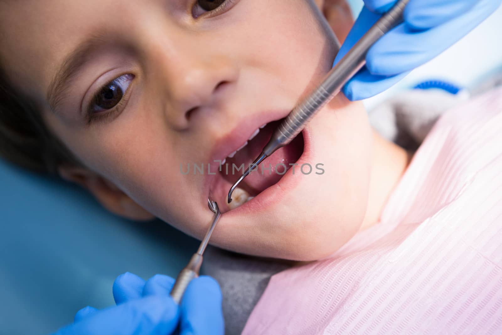 High angle view of dentist giving treatment to boy at medical clinic