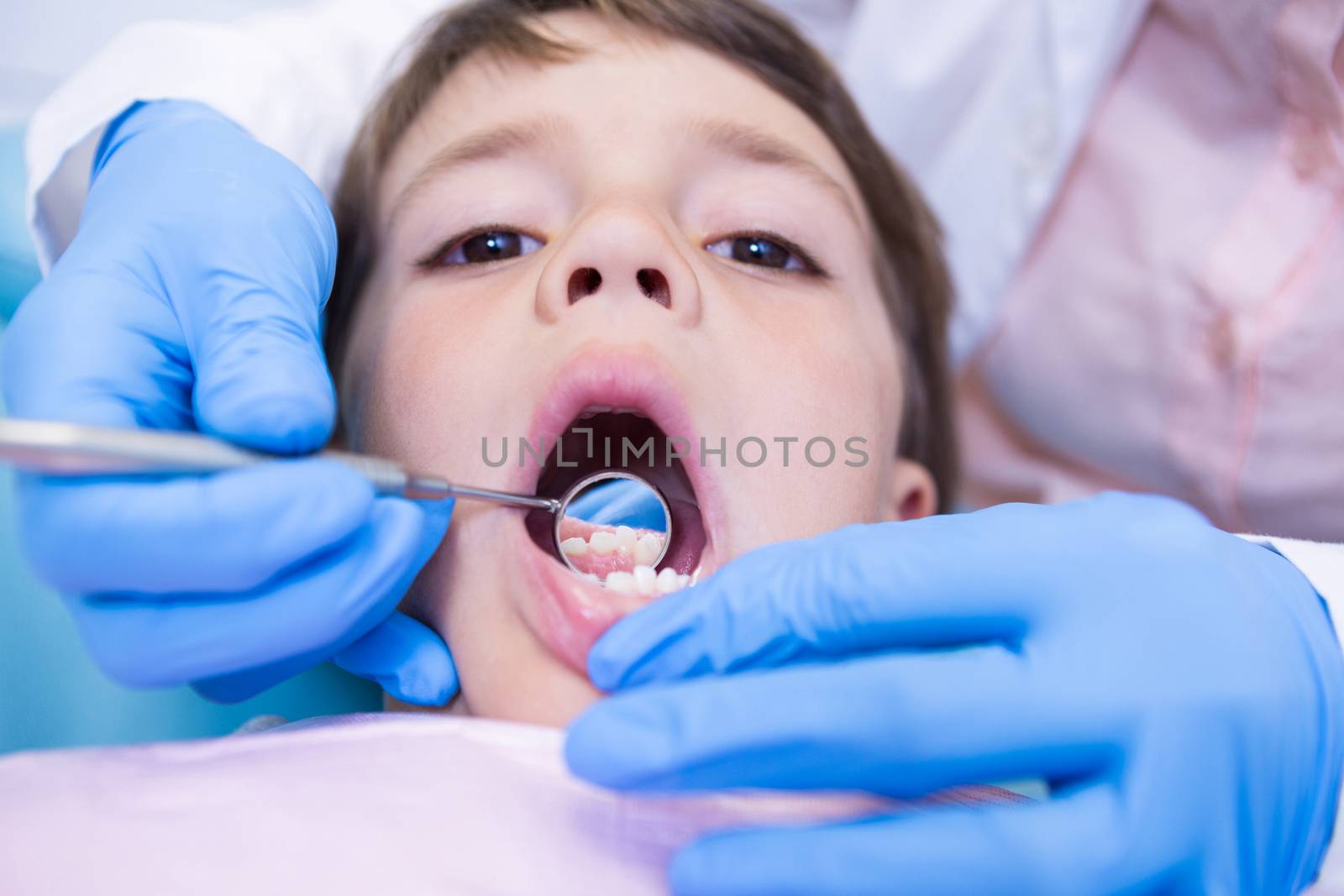 Close up of dentist examining cute boy at clinic