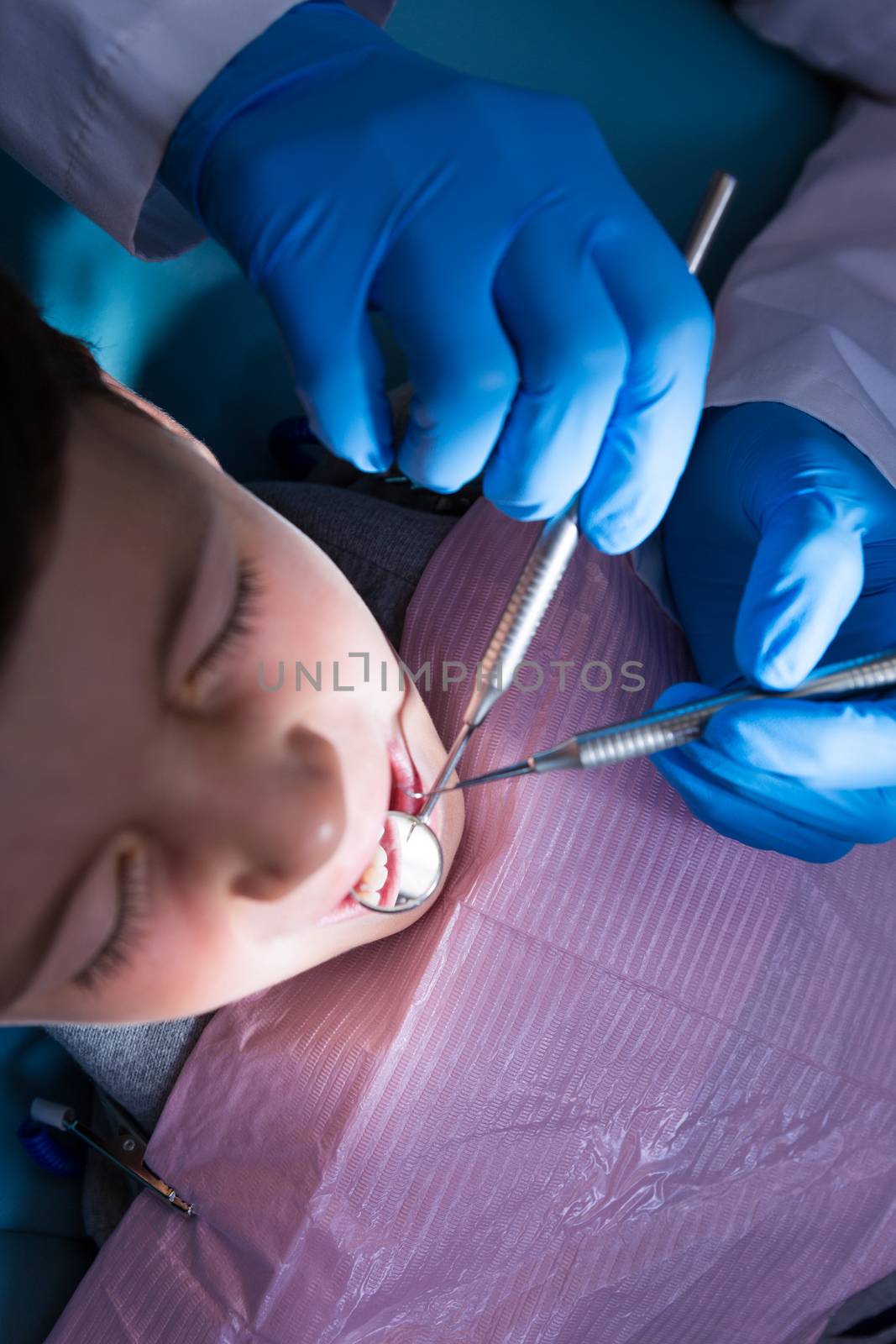 Overhead view of dentist holding medical equipment while examining boy at clinic