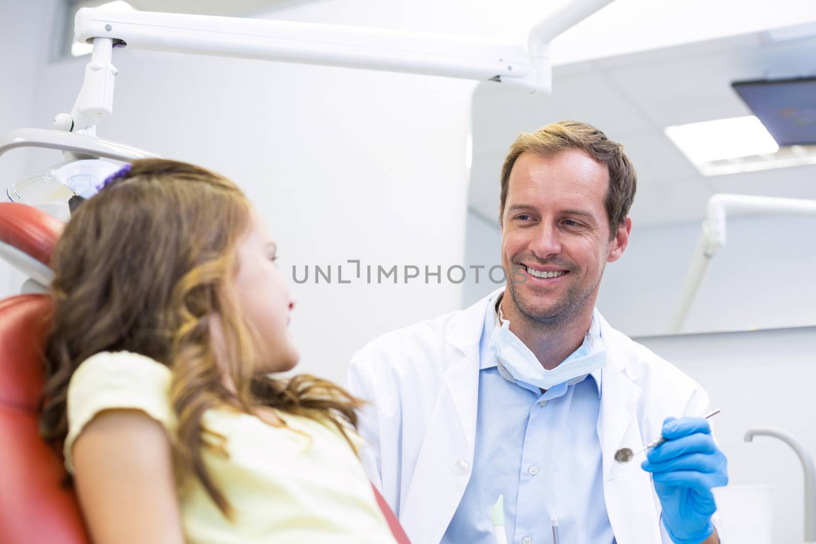 Smiling dentist talking to young patient in dental clinic