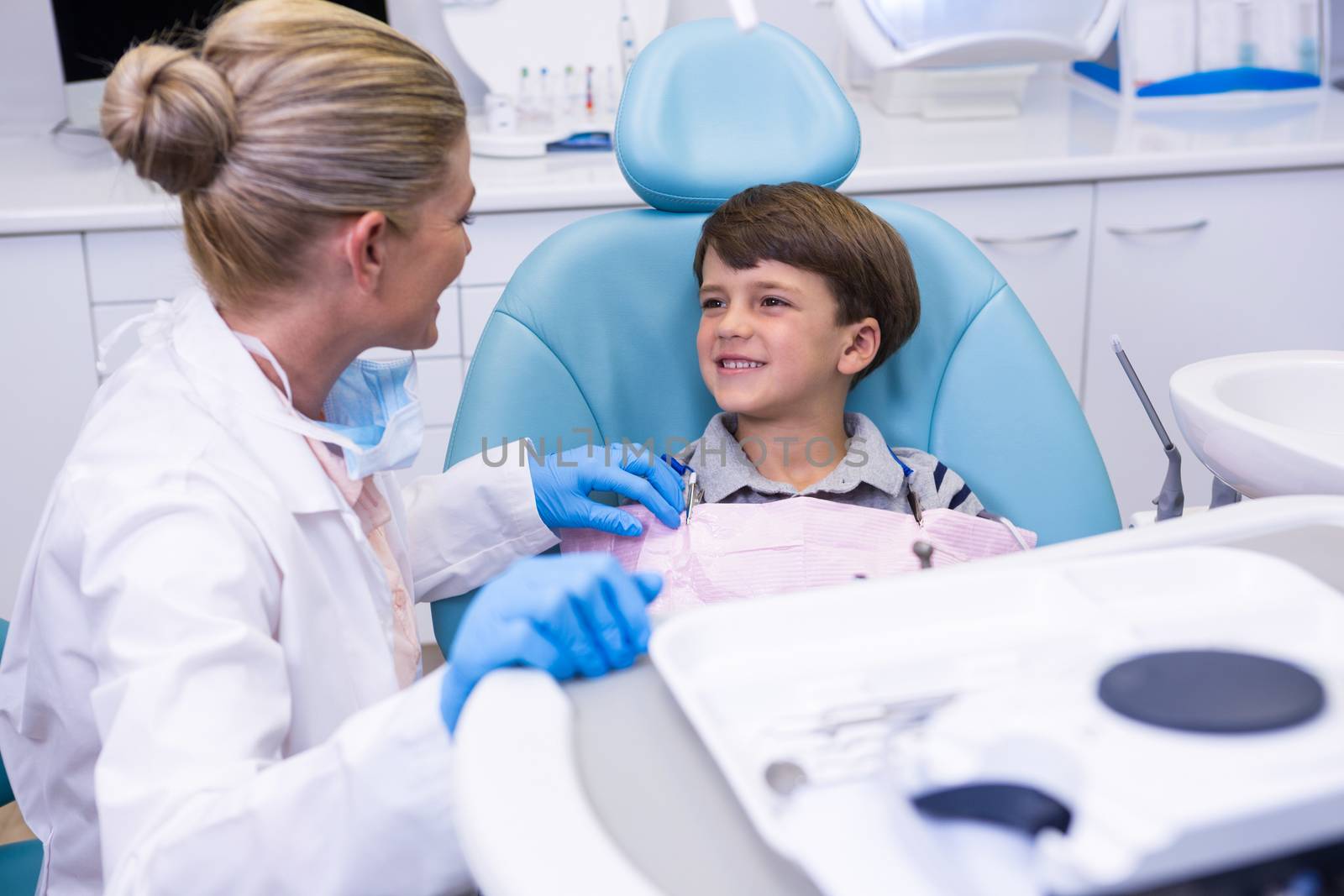 Side view of dentist talking with boy at medical clinic